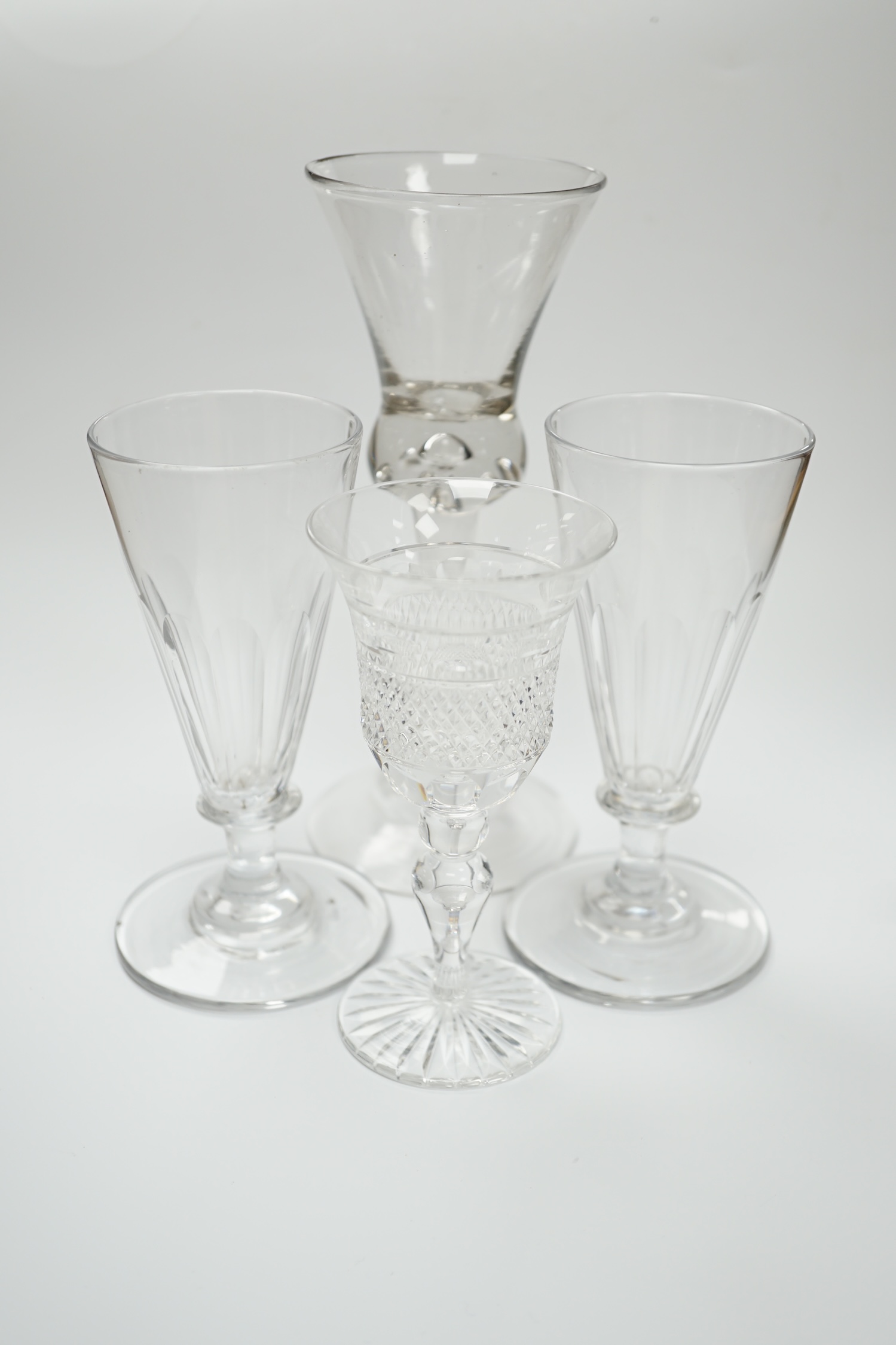 A pair of early 19th century dwarf ale glasses with fluted conical bowls, bladed knop stems and polished pontils, together with a mid-18th century thistle bowl glass with multiple air tears, plain stem and domed foot and